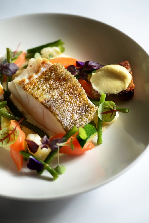 Pavé de cabillaud servi avec légumes croquants et sauce crémeuse à la Brasserie L’Est à Lyon.