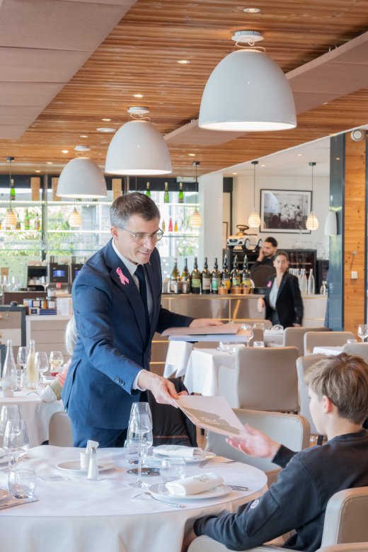 Loïc Jacquand en costume bleu servant un client au Restaurant Fond Rose, à Caluire-et-Cuire.