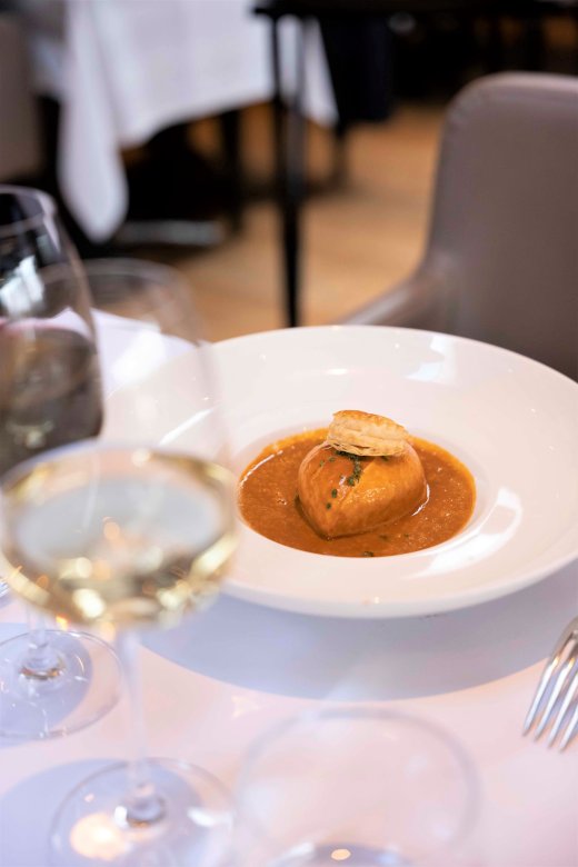 Quenelle de brochet nappée de sauce homardine, servie avec un verre de vin blanc a la Maison Fond Rose à Lyon.