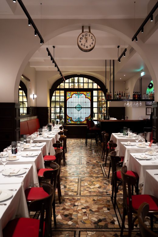 Salle intérieure de la Brasserie Le Nord à Lyon avec vitraux colorés et décor boisé.