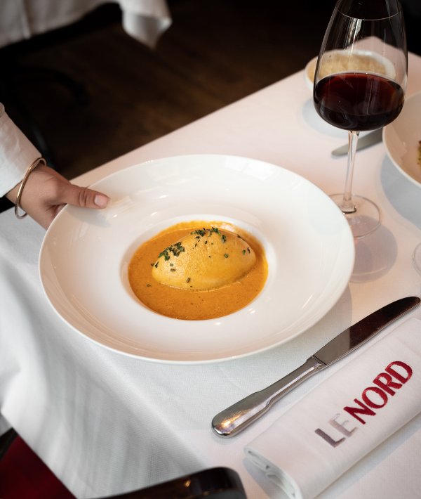 Quenelle de brochet servie à la Brasserie Le Nord avec un verre de vin rouge.