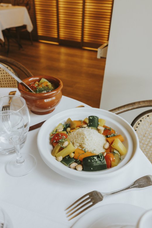 Couscous végétarien servi dans une assiette blanche, accompagné de légumes colorés et d’une semoule fine, à la Brasserie Le Sud à Lyon.