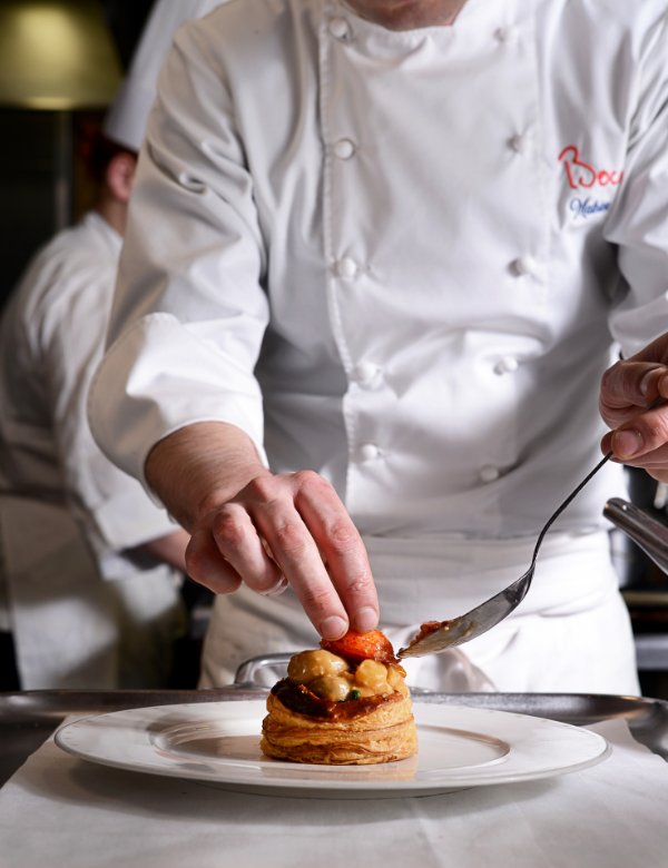 Chef des maisons Bocuse en train de dresser une assiette gastronomique avec précision
