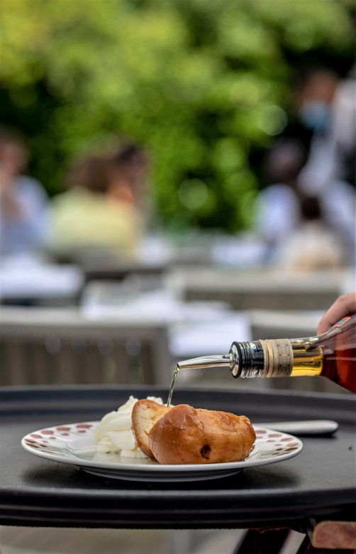 Baba au rhum arrosé devant les tables de la terrasse du Restaurant Fond Rose à Lyon.