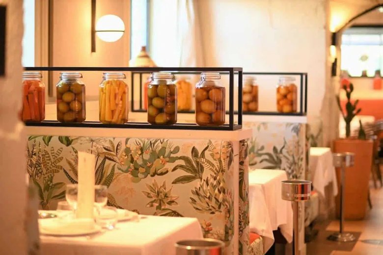 Décor coloré de la Brasserie Le Sud à Lyon avec banquettes florales et bocaux méditerranéens.